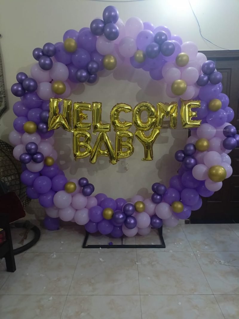 Baby shower setup in Sialkot with purple balloon ring and gold Welcome Baby letters