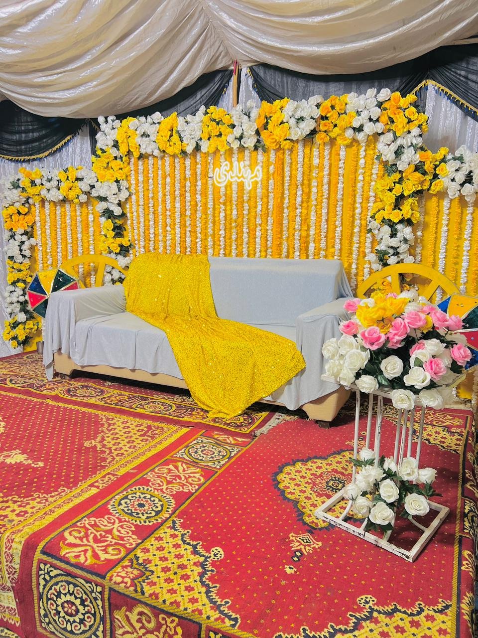 Mehndi or mayun stage with marigold drapes, fairy lights and a sofa in Sialkot – Events In Sialkot