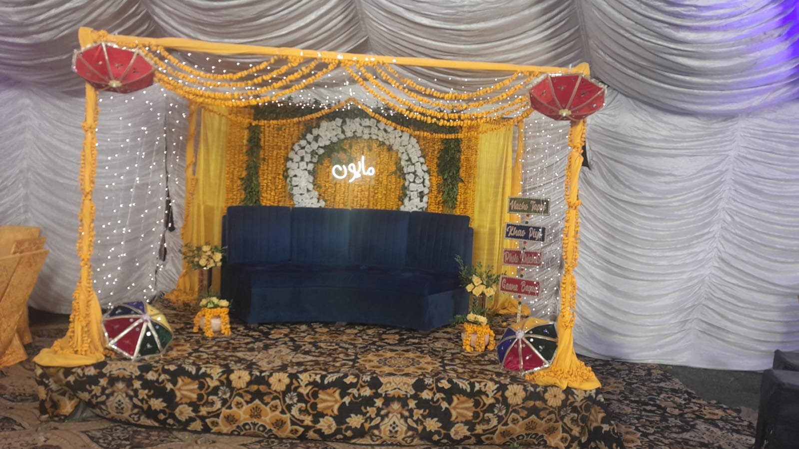 Mehndi or mayun stage with marigold drapes, fairy lights and a sofa in Sialkot – Events In Sialkot